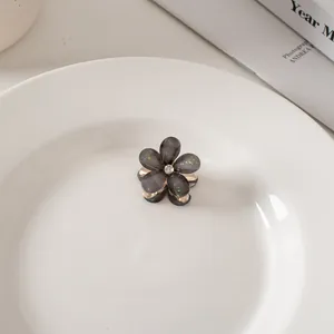 Dettaglio ravvicinato di una mini molletta a fiore con paillettes verdi e un cristallo