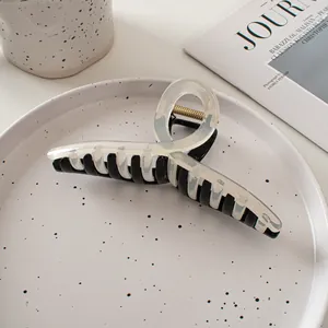 Détail d'une grande pince à cheveux bicolore noir et beige sur une assiette décorative