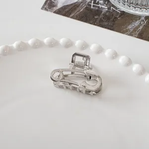 Detailed view of silver metal safety pin hair claw on a white decorative porcelain plate