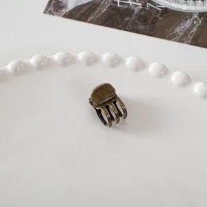 Macro detail of a vintage bronze mini metal hair claw clip with interlocking teeth