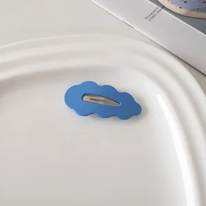 Detailaufnahme einer matt-himmelblauen Haarklammer in Wolkenform auf weißem Tablett