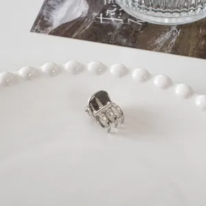 Macro detail of a mini silver metal hair claw clip placed on a white decorative plate
