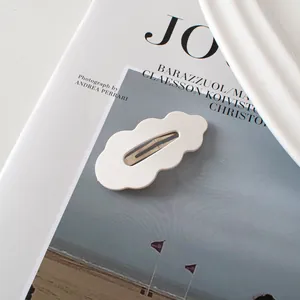Detail einer cremeweißen wellenförmigen BB-Haarklammer auf einer Kunstzeitschrift