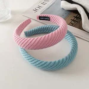 Detail of pink and blue knitted headbands with handmade label on minimalist backdrop