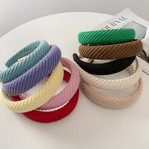 Close-up of thick knitted headbands in nine vibrant colors with a soft ribbed texture