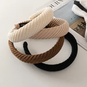 Close-up of thick knitted headbands in beige, brown and black with handmade label texture