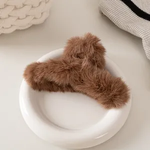 Macro di una pinza per capelli in peluche marrone scuro su piatto bianco in set caldo