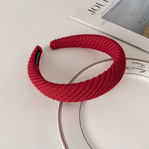 Detail view of red knitted thick headband with a black handmade woven label inside