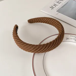Detail of a brown knitted headband with a handmade label and soft ribbed texture finish