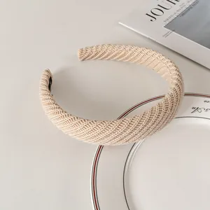 Close-up of beige knit headband with detailed twill weave and internal brand label