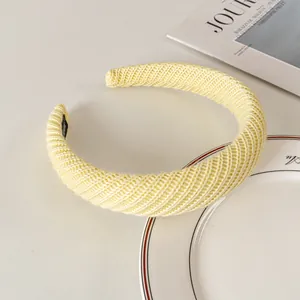 Detail of light yellow chunky knitted headband with soft twill texture on a ceramic plate