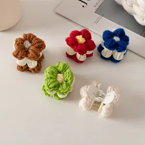 Gros plan de cinq mini pinces à cheveux en fleurs tricotées colorées sur une table