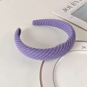Detail of purple chunky cable knit headband on white porcelain dish with elegant textures