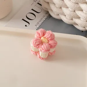 Détail de la pince à cheveux fleur rose tricotée avec centre jaune sur fond chaleureux