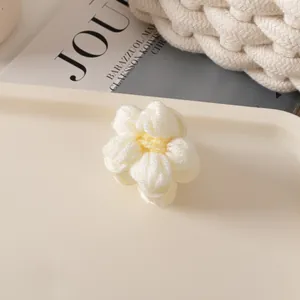 Gros plan d'une pince à cheveux fleur au crochet faite main avec des textures tricotées