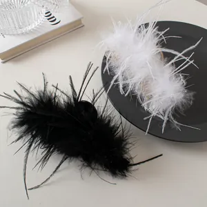 Detail view of fluffy black and white ostrich feather hair clips on a minimalist surface