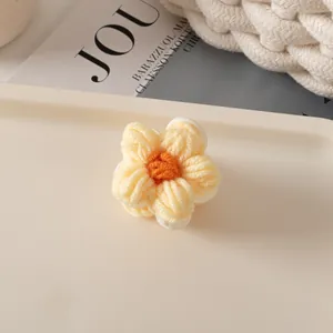 Vue détaillée d'une pince à cheveux fleurie tricotée main sur tissu doux texturé