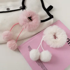 Detail von weichen weißen und rosa Kunstpelz-Pompons Haargummis auf Strickhintergrund