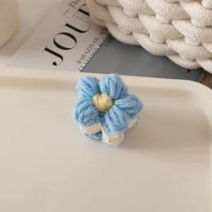 Gros plan d'une pince à cheveux fleur en laine bleue sur un plateau décoratif blanc