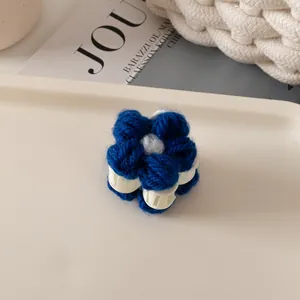 Vue détaillée de la pince à cheveux fleur tricotée bleue avec des détails centraux blancs