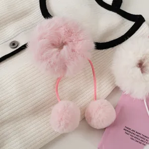 Detail von flauschigen Haargummis mit süßen weichen Pelz-Pompons in Weiß und Rosa