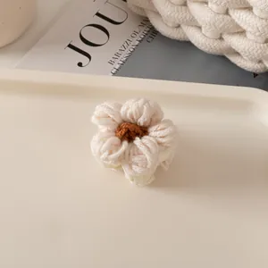 Détail d'une pince à cheveux fleur en tricot fait main en blanc crème et fil marron