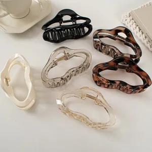 Set of five large liquid-line claw clips in tortoise shell and solid colors on beige desk