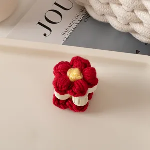 Gros plan d'une pince à cheveux fleur au crochet rouge et jaune avec base blanche