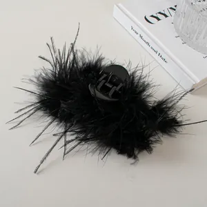 Detail shot of elegant black feather hair claw clip on aesthetic white background