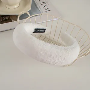 Close-up of white plush headband with HAND MADE label on soft faux rabbit fur