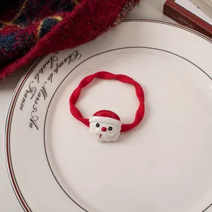 Detail of red elastic hair tie with 3D Santa Claus charm on a festive background