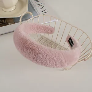 Close-up of pink faux rabbit fur headband with handmade label in a cozy setting