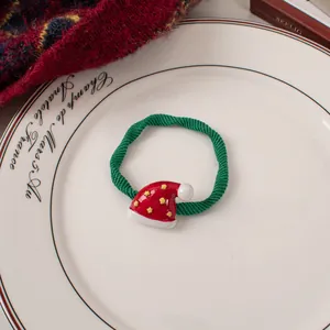 Detail of Christmas hair scrunchie with red hat charm and green elastic cord on a white plate