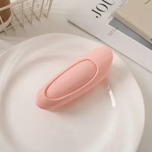Close-up of pink glossy hair root clip on white plate for volume and styling