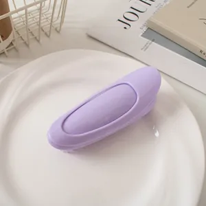 Close-up of a purple silicone scalp massage hair brush on a white decorative plate