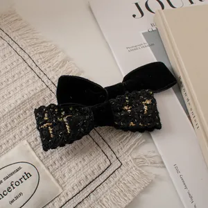 Close-up of vintage black velvet and tweed double bow hair clip with gold metallic accents