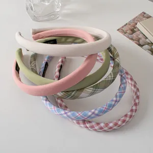 Macro view of six padded fabric headbands featuring solid colors and classic plaid patterns