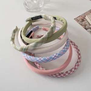Detailed stack of handmade fabric sponge headbands in solid colors and classic plaid patterns