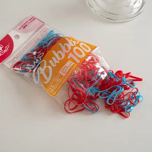Detail of red and blue elastic hair ties spilling from a 100-piece pack for daily styling