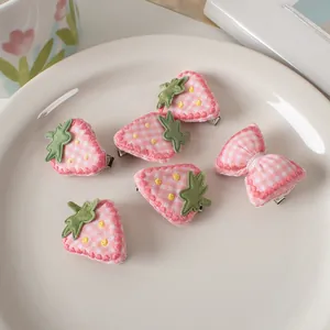 Dettaglio del set di 6 fermagli per capelli con fragole rosa e fiocchi su piatto
