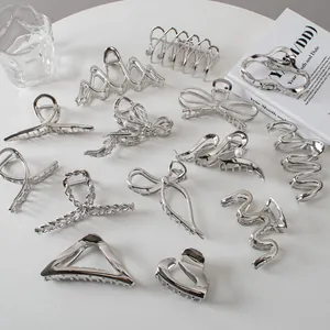 Detailed close-up of various silver metal hair claws with pearls on a white surface
