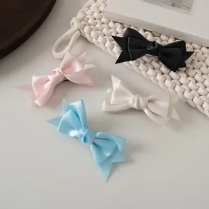 Détail de barrettes à cheveux en satin crème avec double nœud en couleurs pastel