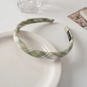 Detail of green plaid fabric headband with handmade tag on a white ceramic plate