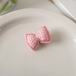 Dettaglio di un fiocco in tessuto a quadretti rosa con cuciture a mano e morbida imbottitura