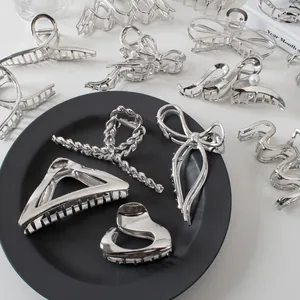 Flat lay of assorted silver metal claw clips with bow and geometric shapes on a tray