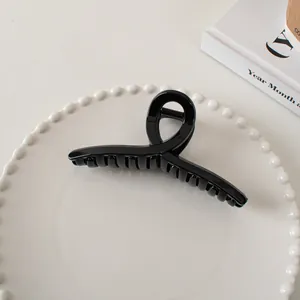 Macro detail of a large glossy black hair claw clip with strong metal spring
