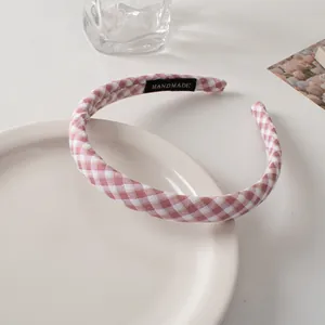 Close-up of pink gingham fabric headband with handmade tag on minimalist ceramic plate