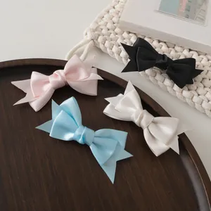 Détail de barrettes à double nœud en satin disponibles en plusieurs coloris doux