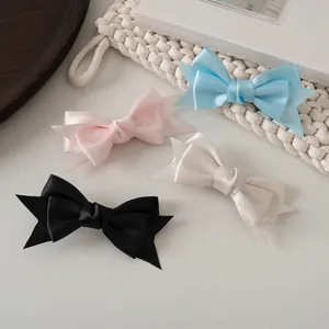 Détail de pinces à cheveux noeud en satin multicouche aux tons pastel sur plateau en bois
