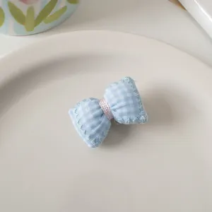 Dettaglio del fermaglio per capelli a fiocco vichy blu su un piatto di ceramica